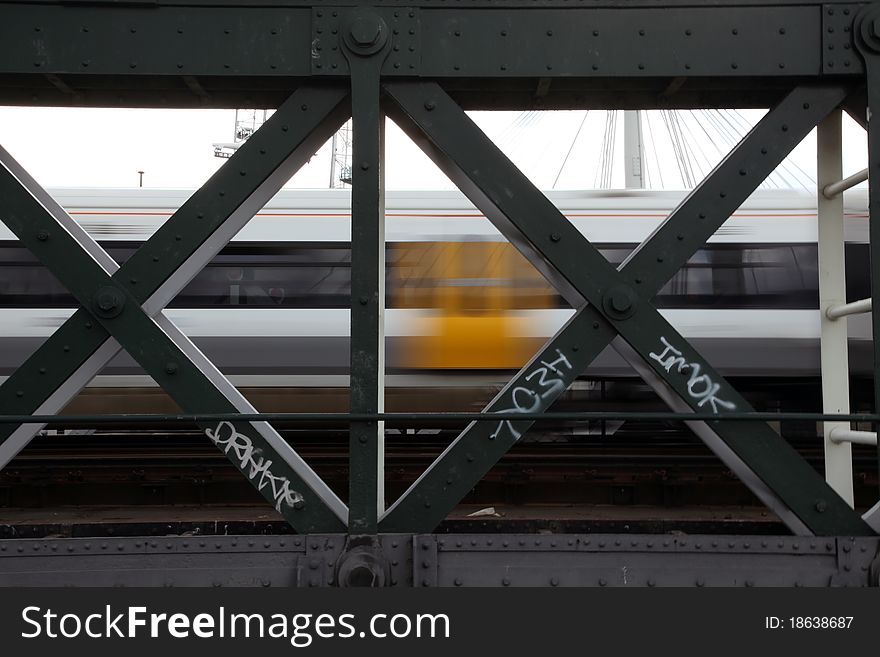 Fast train viewed trackside through steel bridge