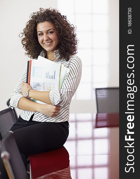 Portrait of beautiful caucasian businesswoman smiling in office, leaning on meeting room table. Vertical shape, front view, copy space. Portrait of beautiful caucasian businesswoman smiling in office, leaning on meeting room table. Vertical shape, front view, copy space