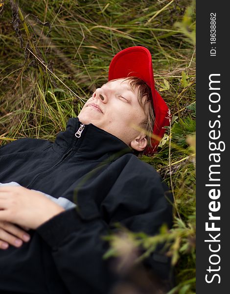 Boy in a stylish red cap resting in a field. Boy in a stylish red cap resting in a field