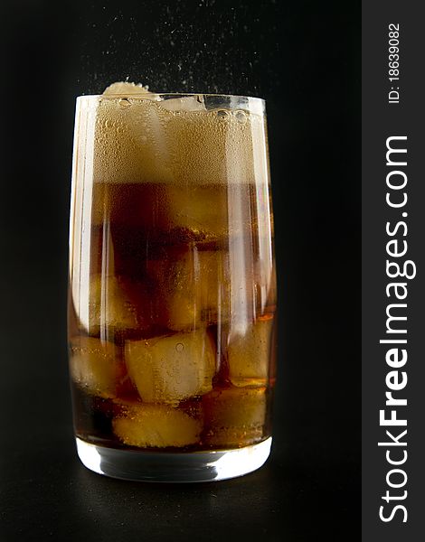 Glass with cola and ice on black background. Glass with cola and ice on black background.