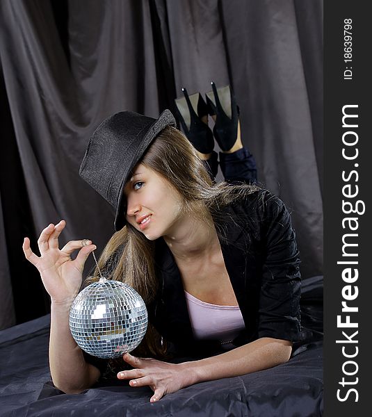 Young beautiful woman with mirrored ball on a grey background.