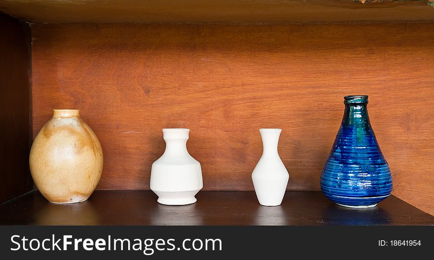 Four earthenwares on wooden shelf in still-life style