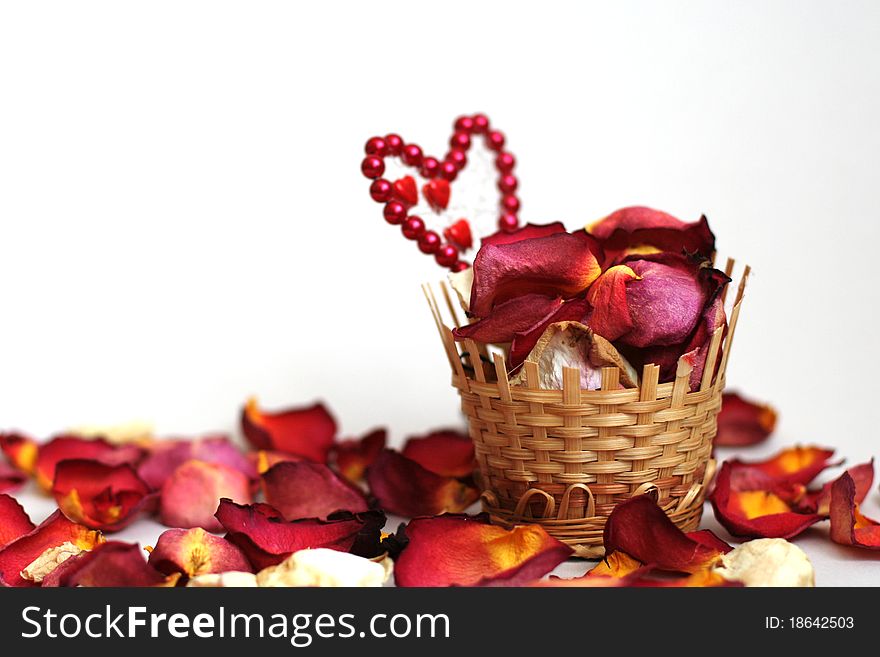 Basket with petals of roses on a white background