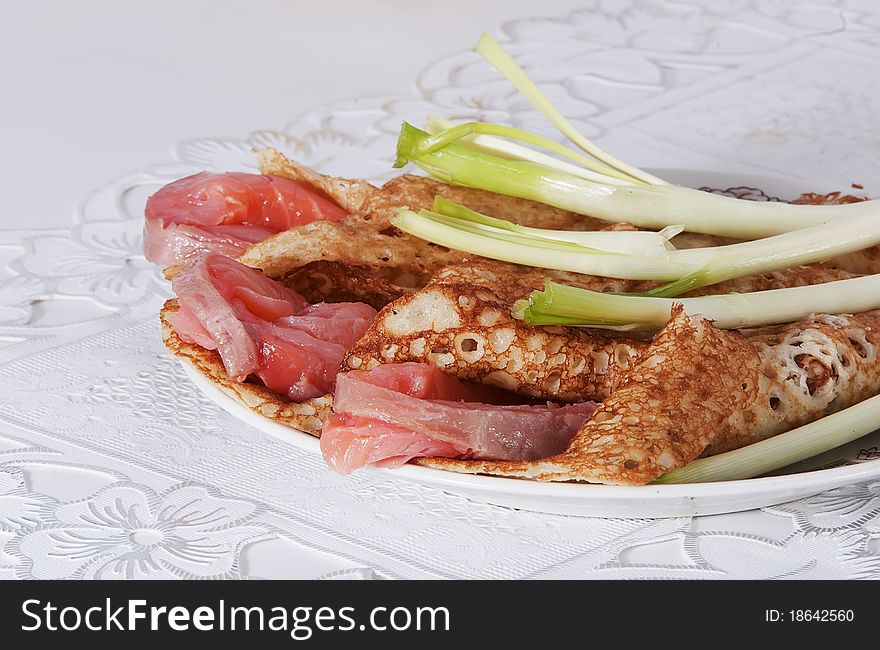 On a table there is a plate with pancakes and red fish. On a light background. On a table there is a plate with pancakes and red fish. On a light background