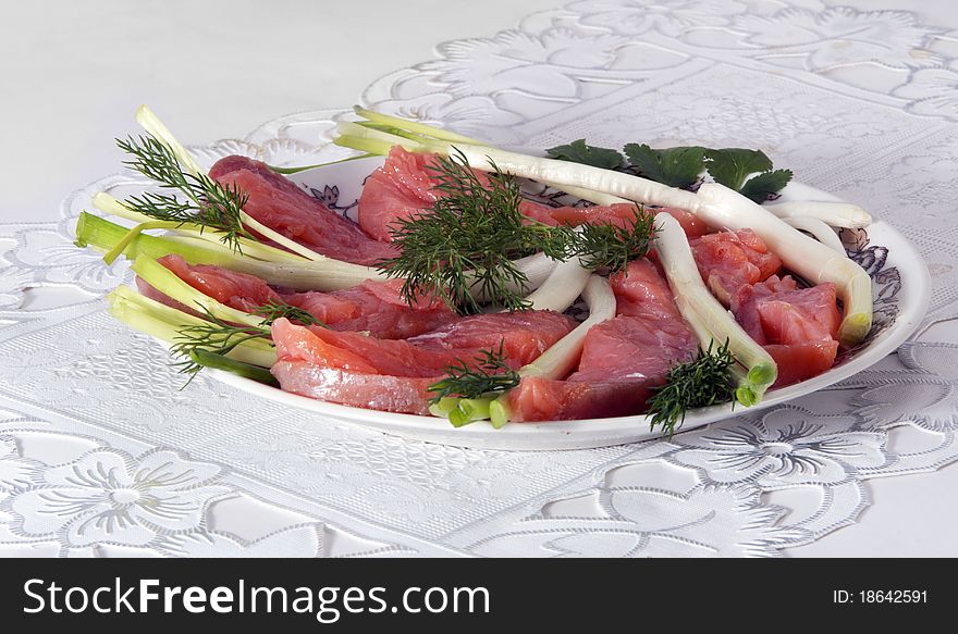 On a table there is a plate with red fish. On a light background. On a table there is a plate with red fish. On a light background