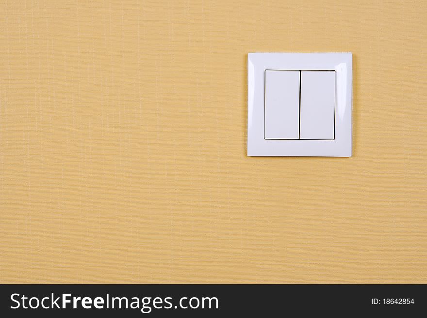 Wall-mounted electric switch in white on a yellow wall