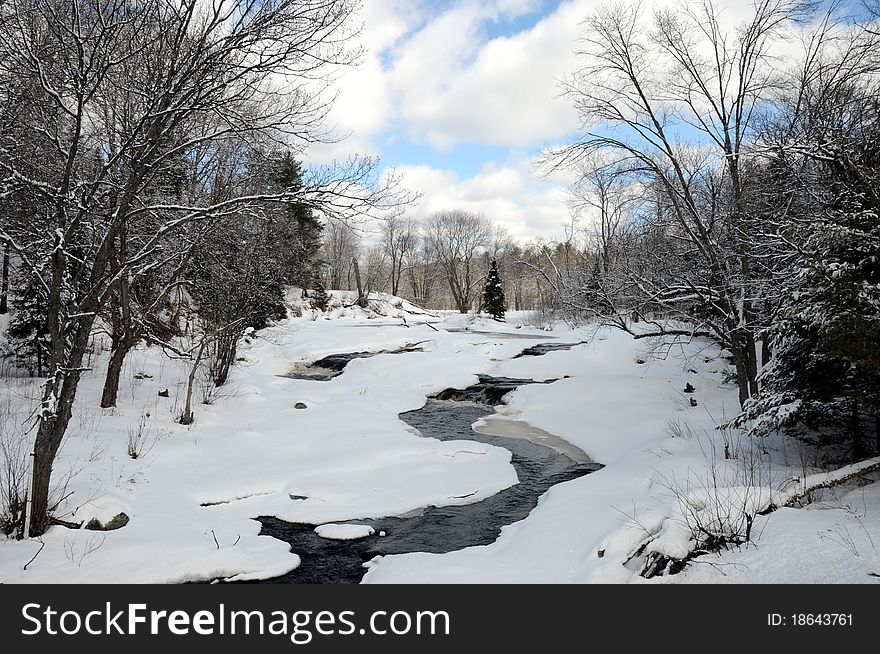 Beautiful river cascading over rocks with trees and blue sky, in winter. Beautiful river cascading over rocks with trees and blue sky, in winter