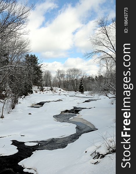 Beautiful river cascading over rocks with trees and blue sky, in winter. Beautiful river cascading over rocks with trees and blue sky, in winter