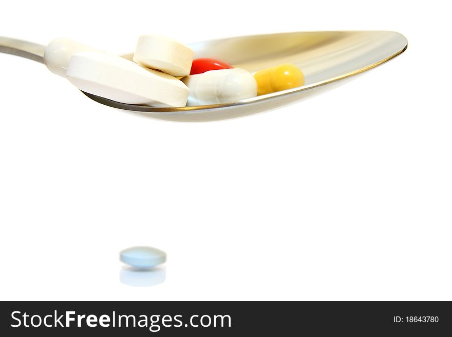 Concept view of different pills and capsules in a spoon. Isolated on a white background. Concept view of different pills and capsules in a spoon. Isolated on a white background