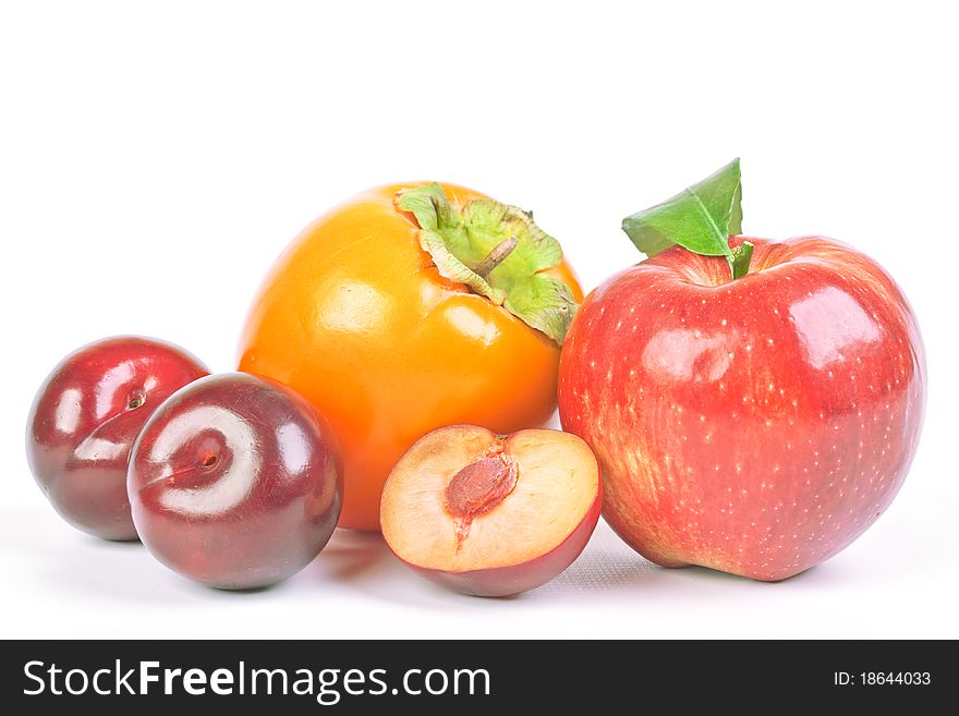 Plums, persimmon and red apple on white background