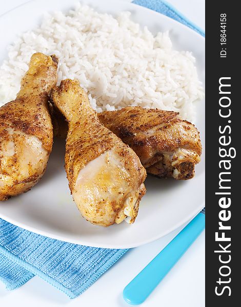 Roasted chicken legs with boiled rice on a plate