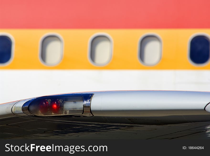 Close up on aircraft windows and red navigation light at wingtip