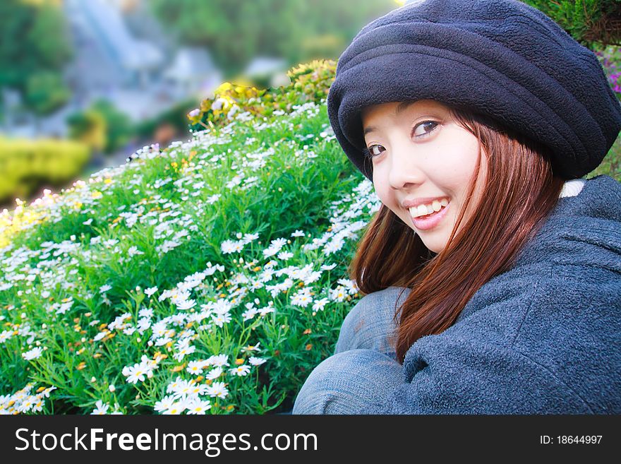 Young woman is smiling in front of flowers garden. Young woman is smiling in front of flowers garden