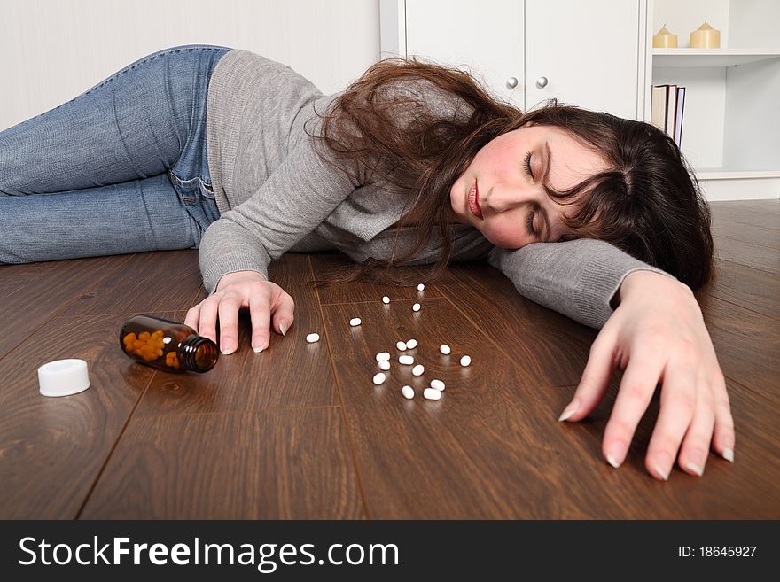 Young woman overdose on pills lying on floor