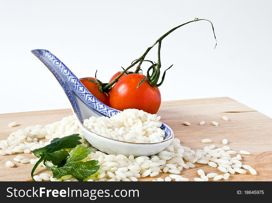 Heap of rice and porcelain spoon with tomato