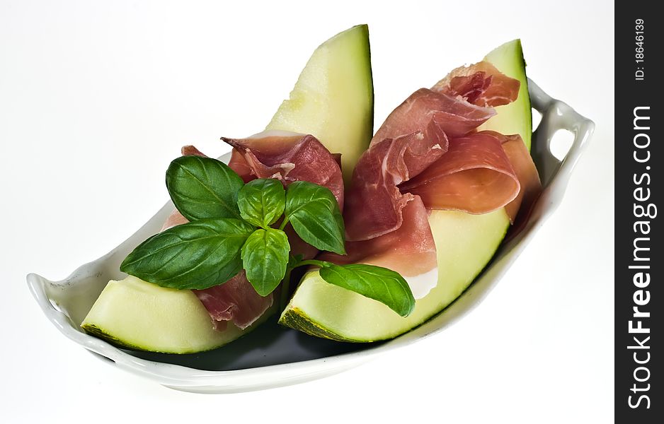 Melon with italian ham and basil leaves on porcelain dish. Melon with italian ham and basil leaves on porcelain dish