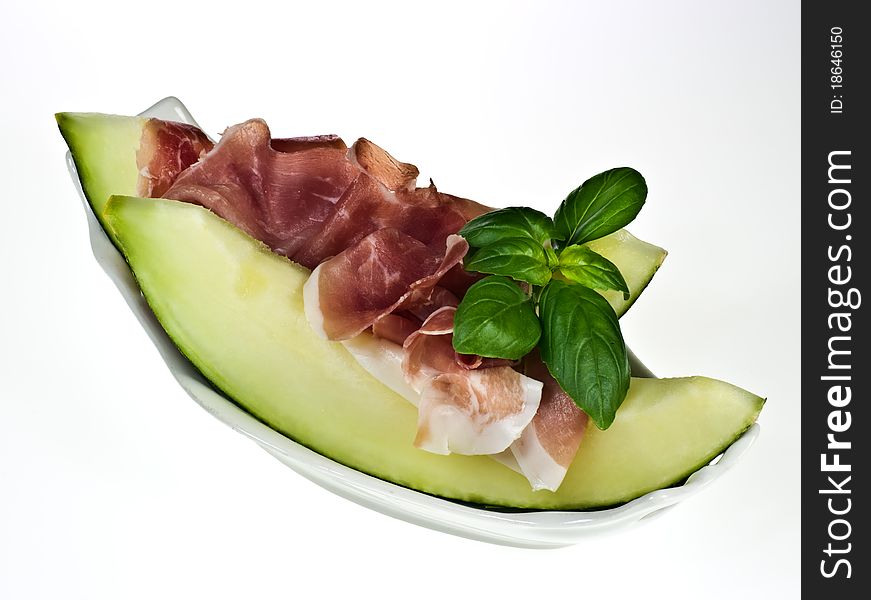 Melon with italian ham and basil leaves on porcelain dish. Melon with italian ham and basil leaves on porcelain dish