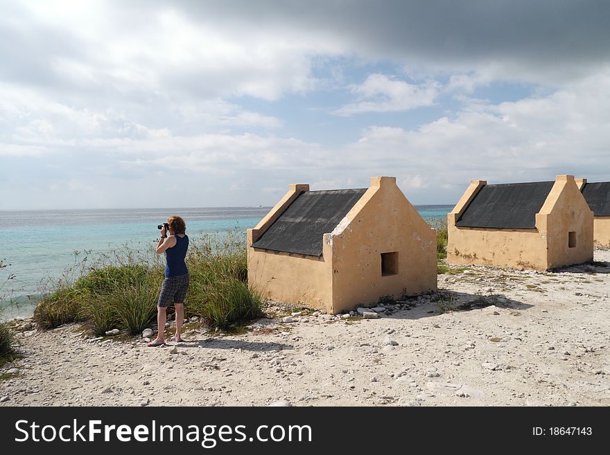 Photographer Tourist and Historic Yellow Slave Huts at the edge of the Caribbean Sea - Bonaire, Netherlands Antilles. Photographer Tourist and Historic Yellow Slave Huts at the edge of the Caribbean Sea - Bonaire, Netherlands Antilles