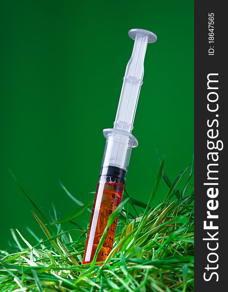 Syringe with red drug stabed in to withered grass. Syringe with red drug stabed in to withered grass