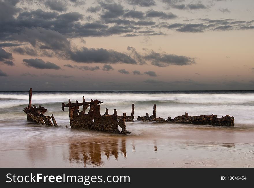 Sunrise with a shipwreck reflecting on the beach. Sunrise with a shipwreck reflecting on the beach