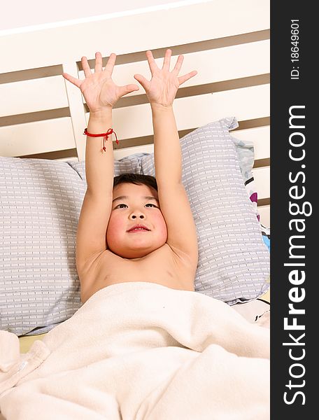 Picture of a little chinese boy yawning while lying on the bed. Picture of a little chinese boy yawning while lying on the bed