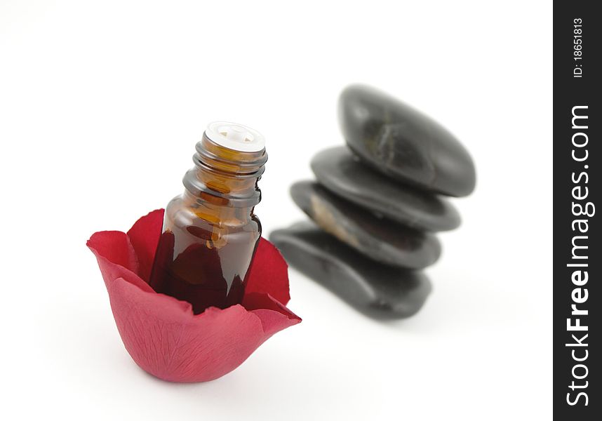 Rose petals, a bottle of aromatherapy oil and spa stones on white. Rose petals, a bottle of aromatherapy oil and spa stones on white