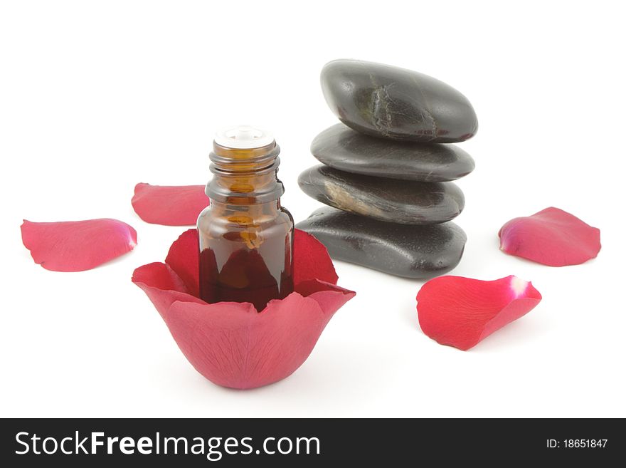 Rose petals, a bottle of aromatherapy oil and spa stones on white. Rose petals, a bottle of aromatherapy oil and spa stones on white