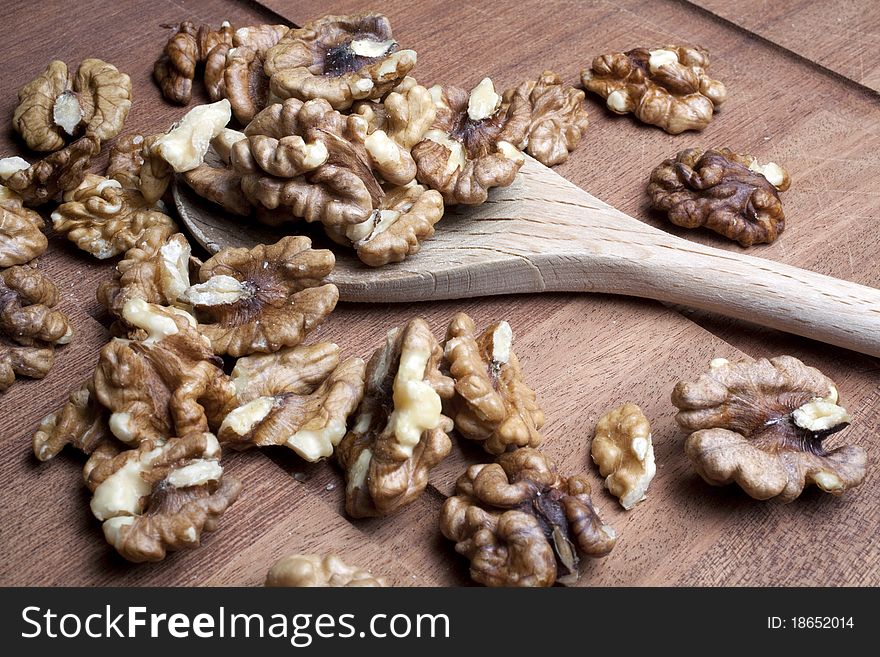 Walnuts on a wooden cutting board inside a kitchen on a wooden spoon