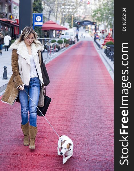 Blond woman walking down the fashion district of a modern city with a jack russel. Blond woman walking down the fashion district of a modern city with a jack russel