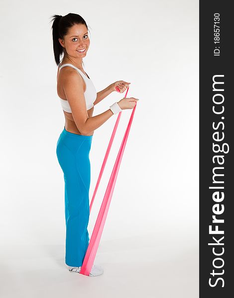 Young woman exercising with rubber ribbon, vertical