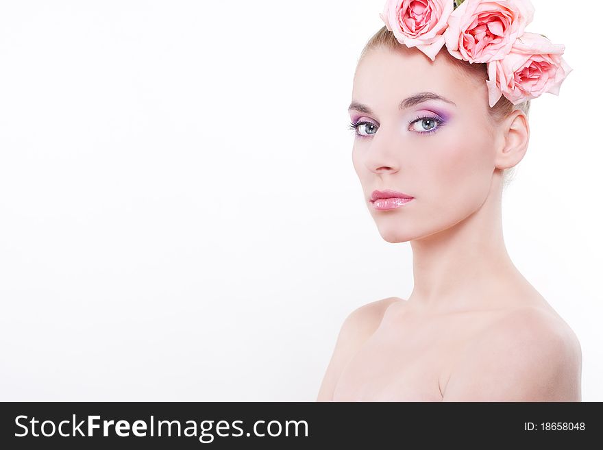 Portrait of young beautiful woman with roses in hair, on white background