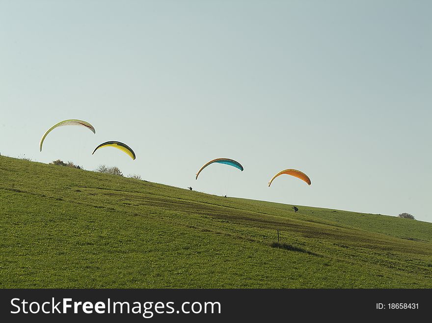 The paragliding people are using the thermal lift. The wind is ballooning the paragliders.