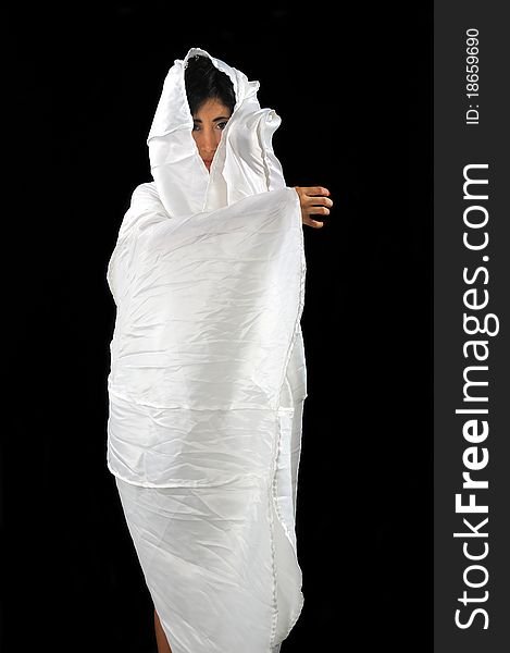 Portrait of a woman wrapped in white fabric isolated on black. Portrait of a woman wrapped in white fabric isolated on black