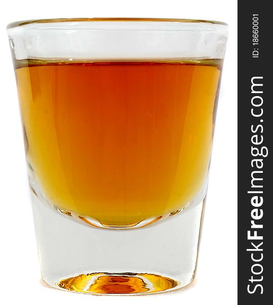 Beautiful side on shot of a shot glass full of brown whiskey or brandy. Beautiful side on shot of a shot glass full of brown whiskey or brandy