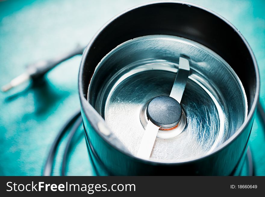 Empty electrical coffee-mill machine on the green tabletop (without top cover)