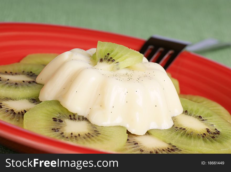 Panna cotta with kiwi slices served on a glass plate.