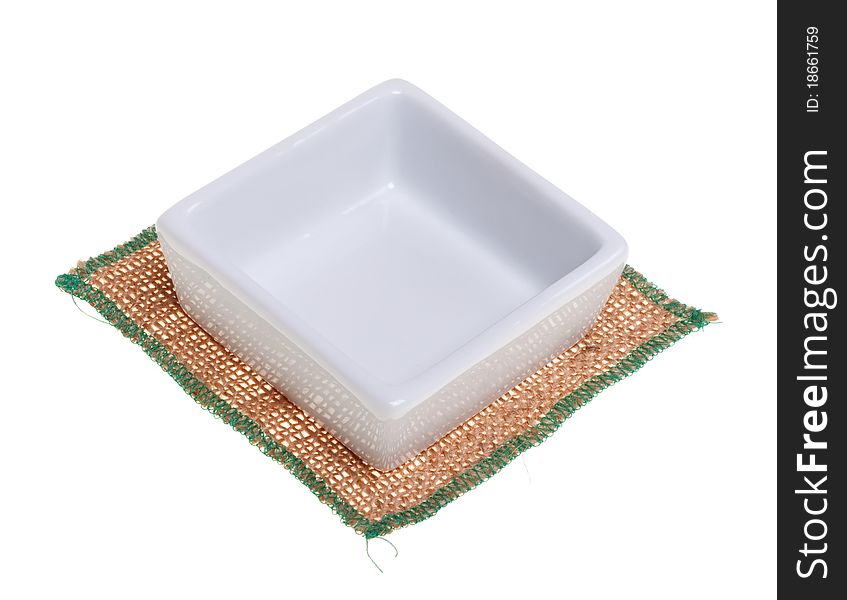 White square dish on a napkin out of burlap, isolated on a white background. White square dish on a napkin out of burlap, isolated on a white background.