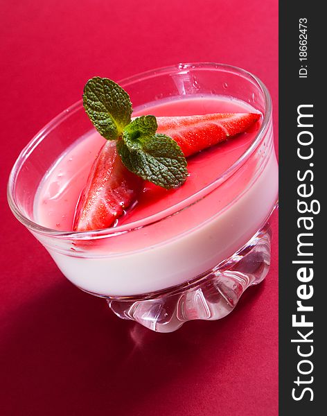 Italian dessert panna cotta on white plate decorated with strawbery, mint and fruit syrup. Italian dessert panna cotta on white plate decorated with strawbery, mint and fruit syrup