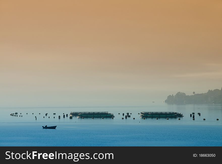 Morning on fishing farm with boat in foreground and plenty copy space