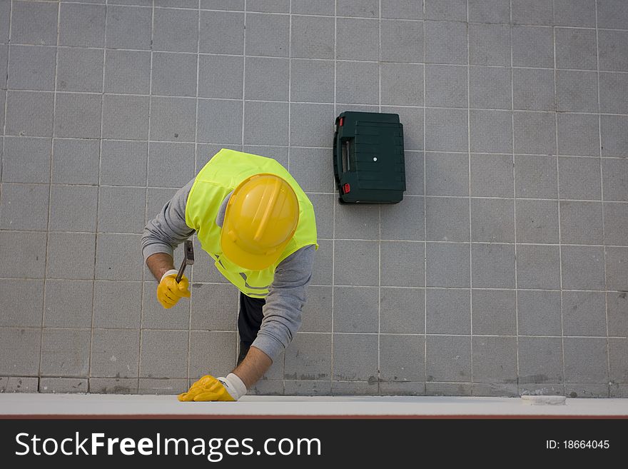 A worker hammering a nail into wall