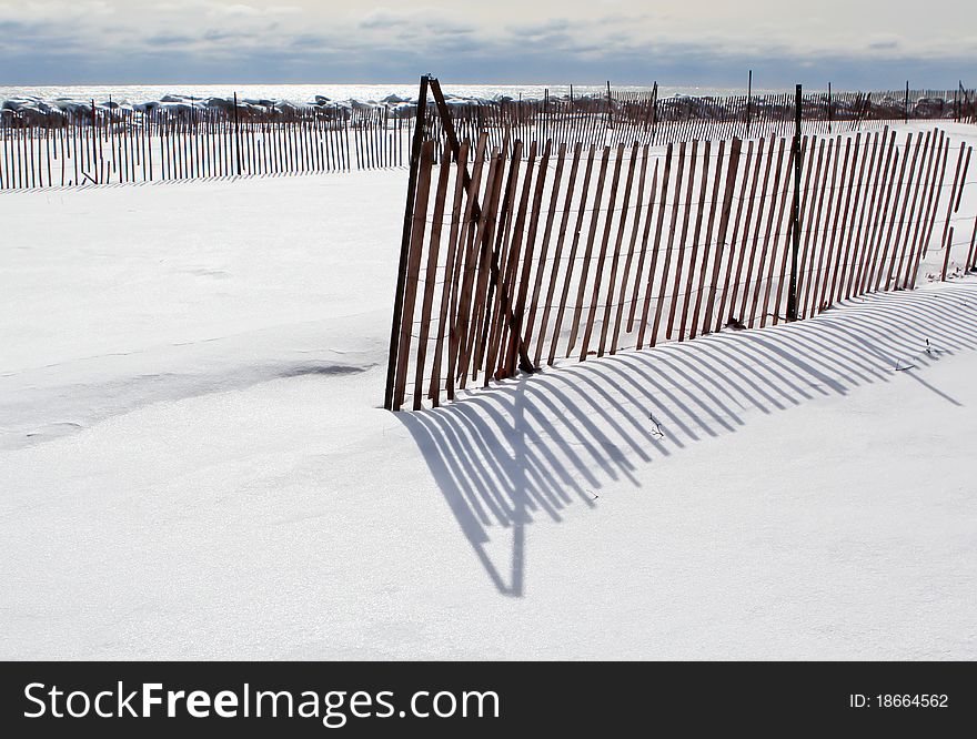 Red snow fence casting shadows on new clean snow