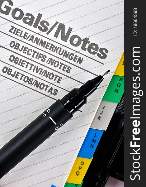 Goals plan or record in notepad and a pen, shown as woking on working goals, target, focus, objective important notes and other related business concept. Goals plan or record in notepad and a pen, shown as woking on working goals, target, focus, objective important notes and other related business concept.