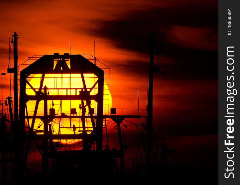 Sun setting behind silhouette of fishing boat. Sun setting behind silhouette of fishing boat