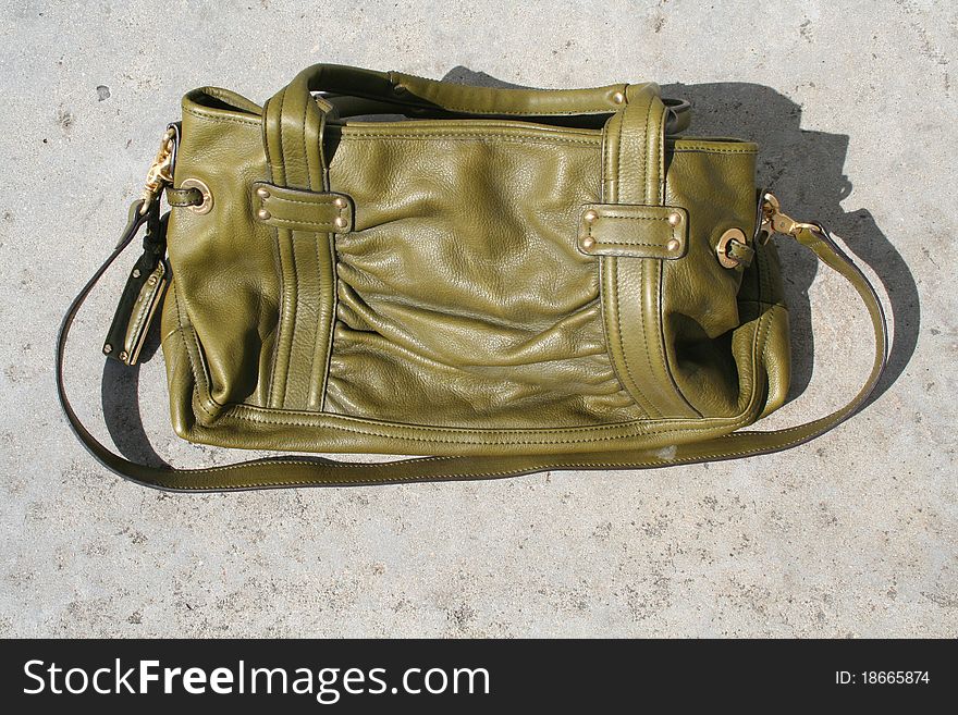 Green leather hand bag set on the ground. Green leather hand bag set on the ground.