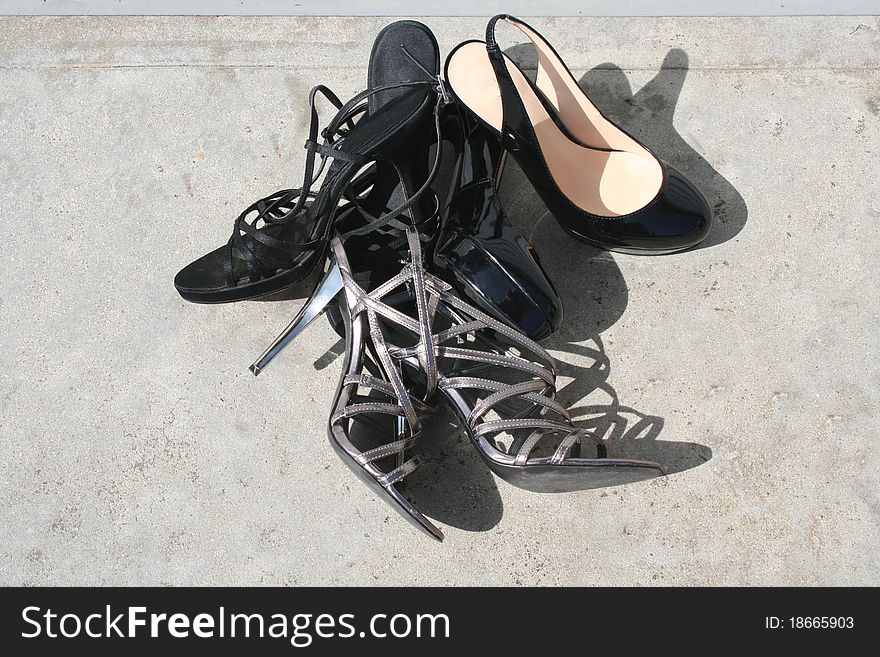 Three separate women's shoes lined up on theground. Three separate women's shoes lined up on theground.