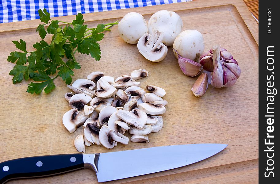 Wooden cutting board with fungi, garlic, parsley and a knife. Wooden cutting board with fungi, garlic, parsley and a knife