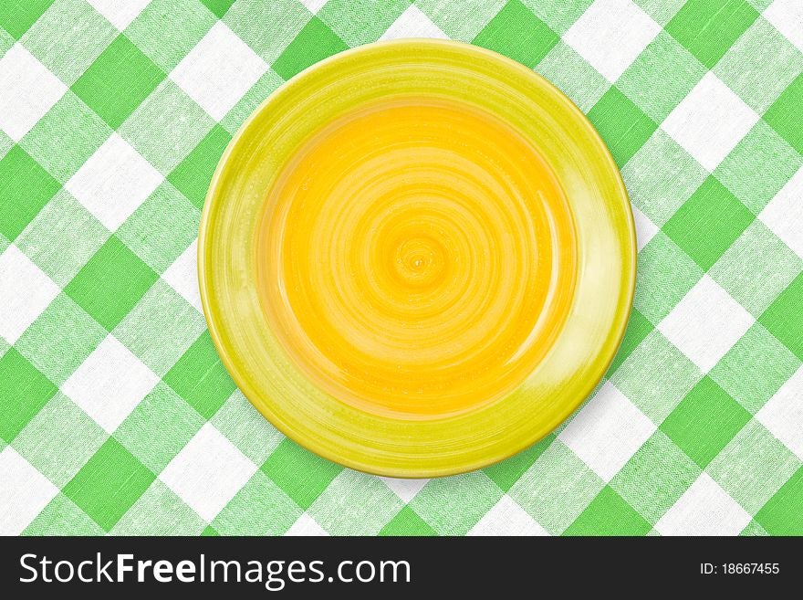 Round yellow plate on green checked tablecloth