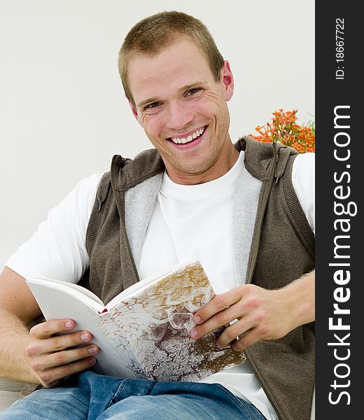Young adult reading a book while he's lying on the couch. Young adult reading a book while he's lying on the couch