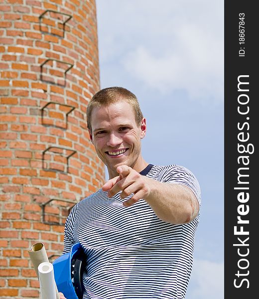 Successful man pointing to you in front of a brick building