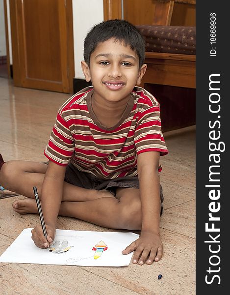 An handsome Indian kid doing his homework very happily